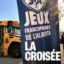 En avant plan, une bannière annonçant les Jeux. En arrière plan, un autobus scolaire. Photo d'archives.