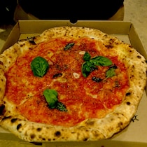 Une pizza recouverte de sauce tomate et de feuilles de basilic