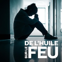 Une personne assise dans un couloir sombre.