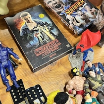 Des figurines et autres trésors entourent un faux coffret VHS de la saison 1 de « Stranger things ».