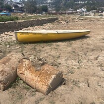 Une barque repose aux abords d'un lac desséché.