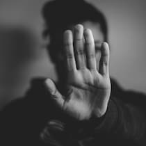 Une femme se défend, en montrant la main en signe «d'arrêt».