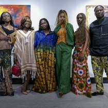 Yemz, Isaac Gelin et des mannequins se tiennent devant les oeuvres de Xavier Mutshipayi. 