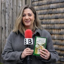Une femme tenant un livre d'Anne la maison aux pignons verts.
