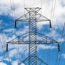 Un pylône électrique sur un fond de ciel bleu et de nuages blancs.