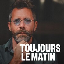 Un homme qui pose avec une main appuyée sur son menton.