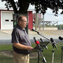Peter Carpenter parle dans un micro, à l'extérieur de la ferme Schuttens Holsteins.