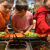 Des enfants se servent dans un buffet à l'école.