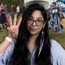 L’animatrice Jemmy Echaquan Dubé est au premier plan, souriante et levant trois doigts, sur un fond de pow-wow en plein air avec des danseurs en régalia et une grande tente blanche.