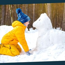 Une petite fillette fait un chien dans la neige.
