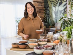 La nutritionniste Geneviève O'Gleman est debout devant un comptoir de cuisine sur lequel il y a plusieurs bols contenant différentes légumineuses.