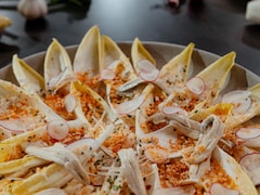 Des endives dans une assiette avec des anchois, des radis et de la chapelure épicée
