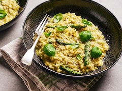 Du risotto aux asperge garni de feuilles de basilic dans un bol.
