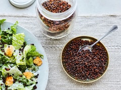 Un bol contenant du simili bacon de lentilles, accompagné d’une salade sur une table.