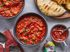Deux bols de soupe harissa aux poivrons grillés sur un comptoir, accompagnés de pains pitas.