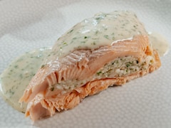 Un morceau de truite garni de mousseline de crevettes et recouvert de sauce aux herbes.