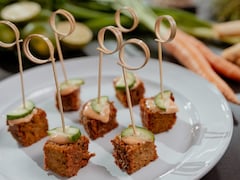 Des cubes de végépâté garni de sauce et de concombres.