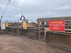 Des barrières délimitent le site de construction. Une grue et une pelleteuse s'activent sur le futur nouveau quai d'Abram-VIllage.
