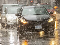Des voitures, sous une neige légère, à l'angle des rues Front et Simcoe à Toronto.