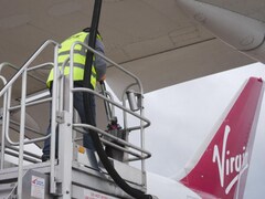 Un employé s'affaire à alimenter un avion de la compagnie Virgin en carburant.