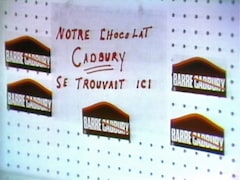 Étagère vide avec des autocollants de la campagne « On barre Cadvury » et une enseigne indiquant « Notre chocolat Cadbury se trouvait ici ».