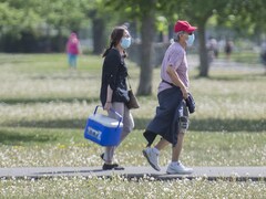 Un homme et une femme portant un masque marchent dans un parc.