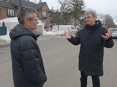 Deux hommes discutent dans un quartier résidentiel, l'hiver. 