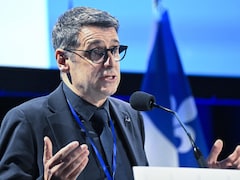 Eric Duhaime parle dans un micro devant un drapeau du Québec