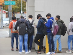 Des étudiants attendent en file à l'extérieur d'un bâtiment.