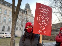 Une enseignante porte une affiche rouge sur laquelle on peut lire Nous, les enseignantes, lançons un cri du coeur