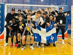 Les joueurs posent en équipe devant le but avec un drapeau du Québec. 