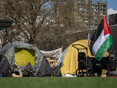Une étudiante en train de lire est allongée près de sa tente sur le campement érigé à UBC, aux côtés d'un drapeau palestinien. 
