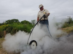 Un homme procède à l'élimination de plants d'herbe à poux avec de l'Eau chaude