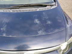Le capot d'une voiture Honda Civic montrant des signes de dégradation dans la peinture bleue.