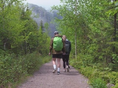 Deux personnes marche dans un sentier en forêt.