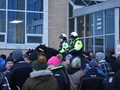 Des policiers à cheval se trouvent devant une entrée de l'édifice. 