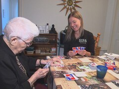 Une jeune femme qui joue aux cartes avec une femme âgée.