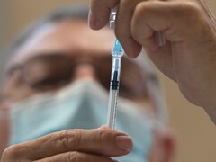 Un médecin manipule une seringue de vaccin.