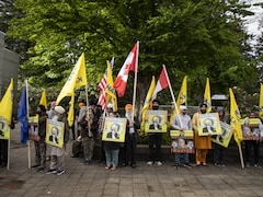 Des partisans et des membres de la famille du militant sikh assassiné en Colombie-Britannique tiennent des drapeaux et des pancartes. 