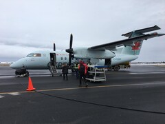 Des passagers qui embarquent dans un avion à l'aéroport des Îles-de-la-Madeleine.