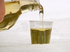 Un liquide jaune pâle versé dans un petit verre déposé sur de la neige.