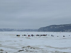 Des cabanes et des tentes sont installées sur les glaces d'une baie.