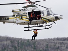 Une personne descend en rappel d'un hélicoptère de la Sûreté du Québec.