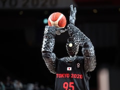 Un robot humanoïde de couleur noire mesurant 210 cm (près de 7 pieds) tient un ballon de basketball dans une main et s'apprête à lancer.