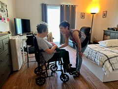 Linda Caron parle avec Paulette Bélanger qui est assise dans une chaise roulante.