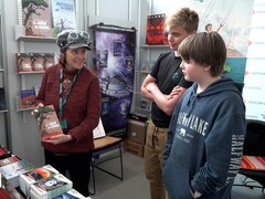 Une autrice tient son livre dans ses mains et le présente à deux jeunes élèves.