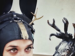 Une personne avec une installation sur la tête, à côté d'une sculpture en métal.