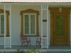 balcon d'une maison de ferme avec deux chaises vides.
