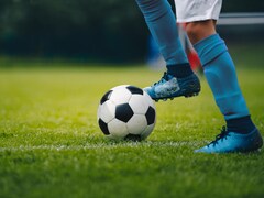 Plan au dessous des genoux d'un joueur de soccer, qui a le pied sur un ballon.