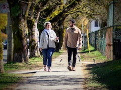 Une femme et un homme marchent sur un trottoir en discutant.